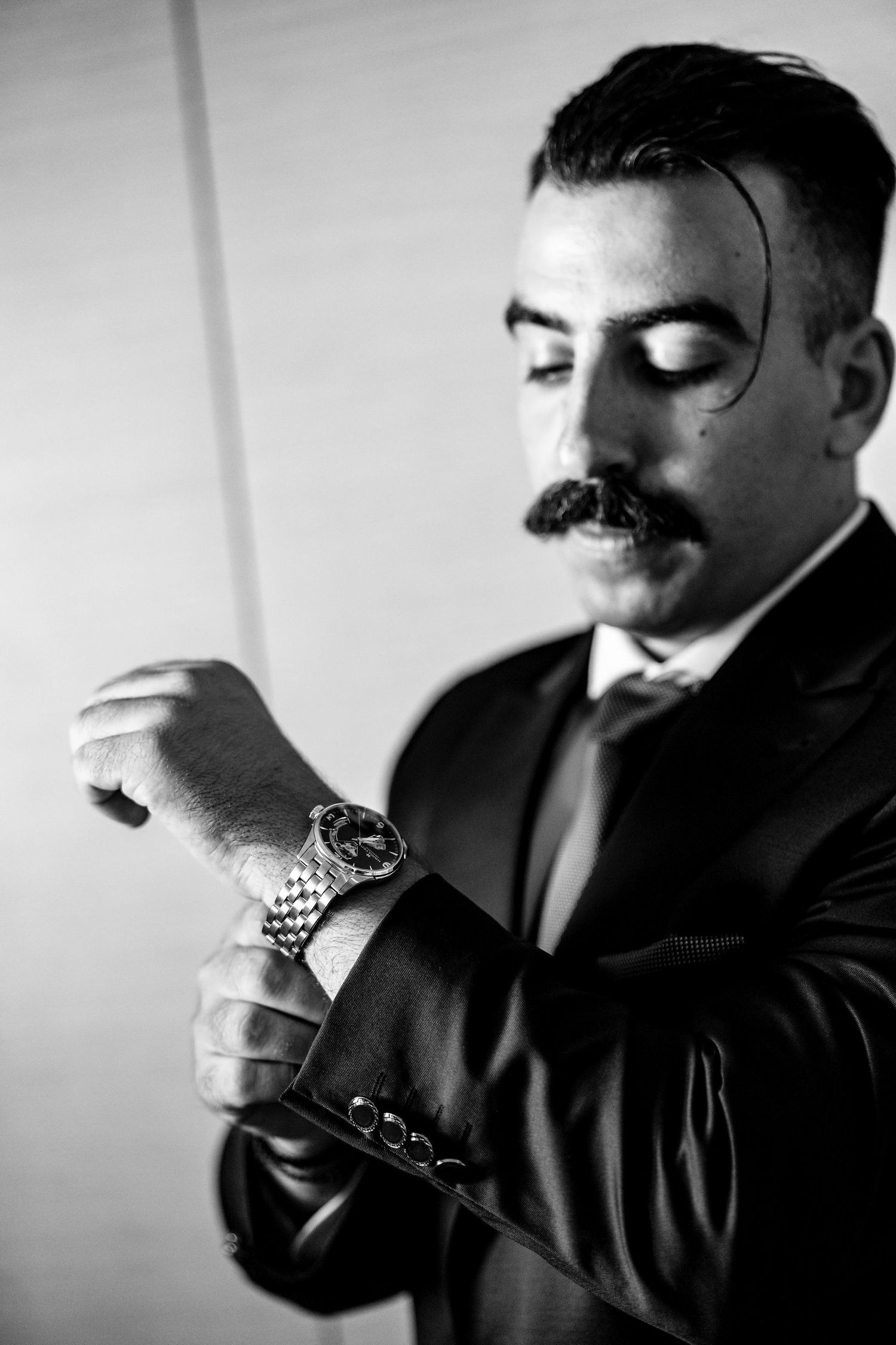Black and white series of a person adjusting their tie in dramatic lighting.