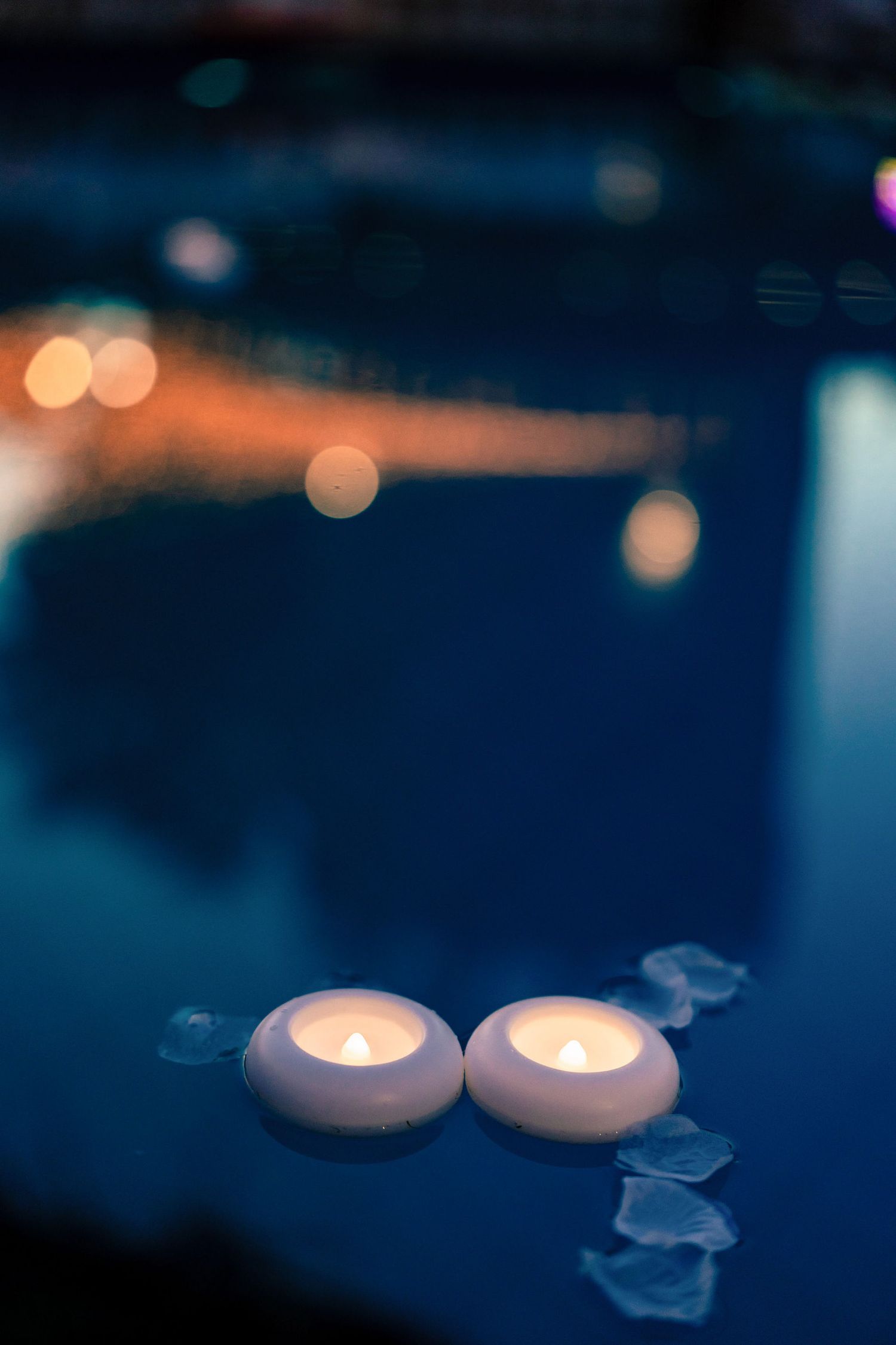 Floating candles creating a romantic ambiance with bokeh effect in dark blue tones.