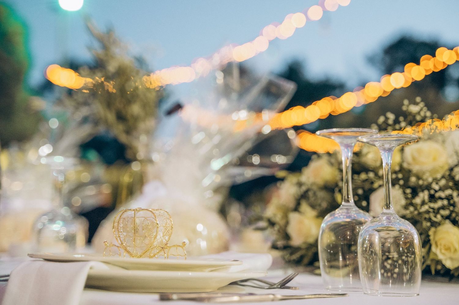 String lights and elegant table settings create a romantic outdoor reception atmosphere.