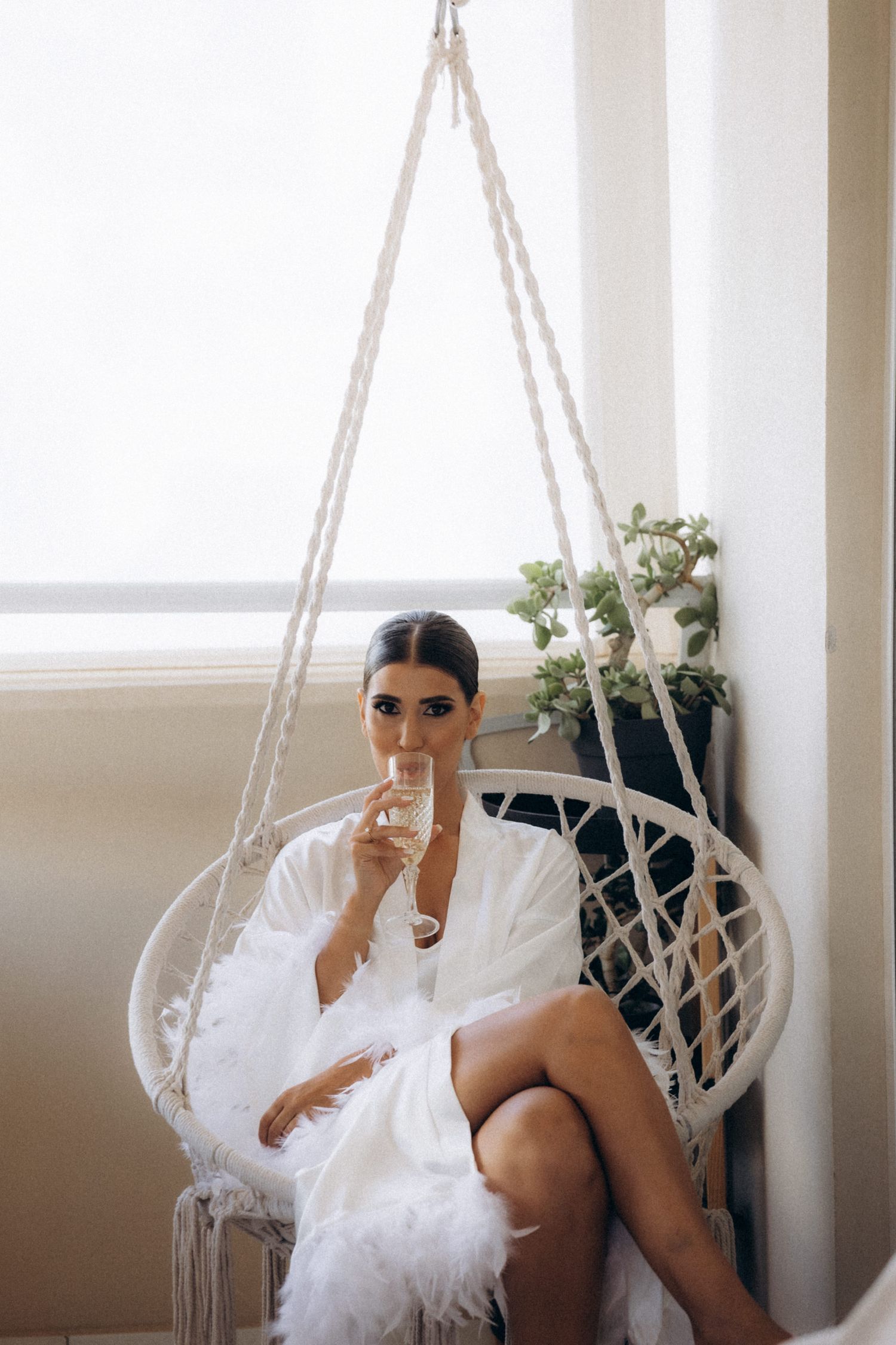 Elegant white hanging chair decorated with tulle in a bright modern room.