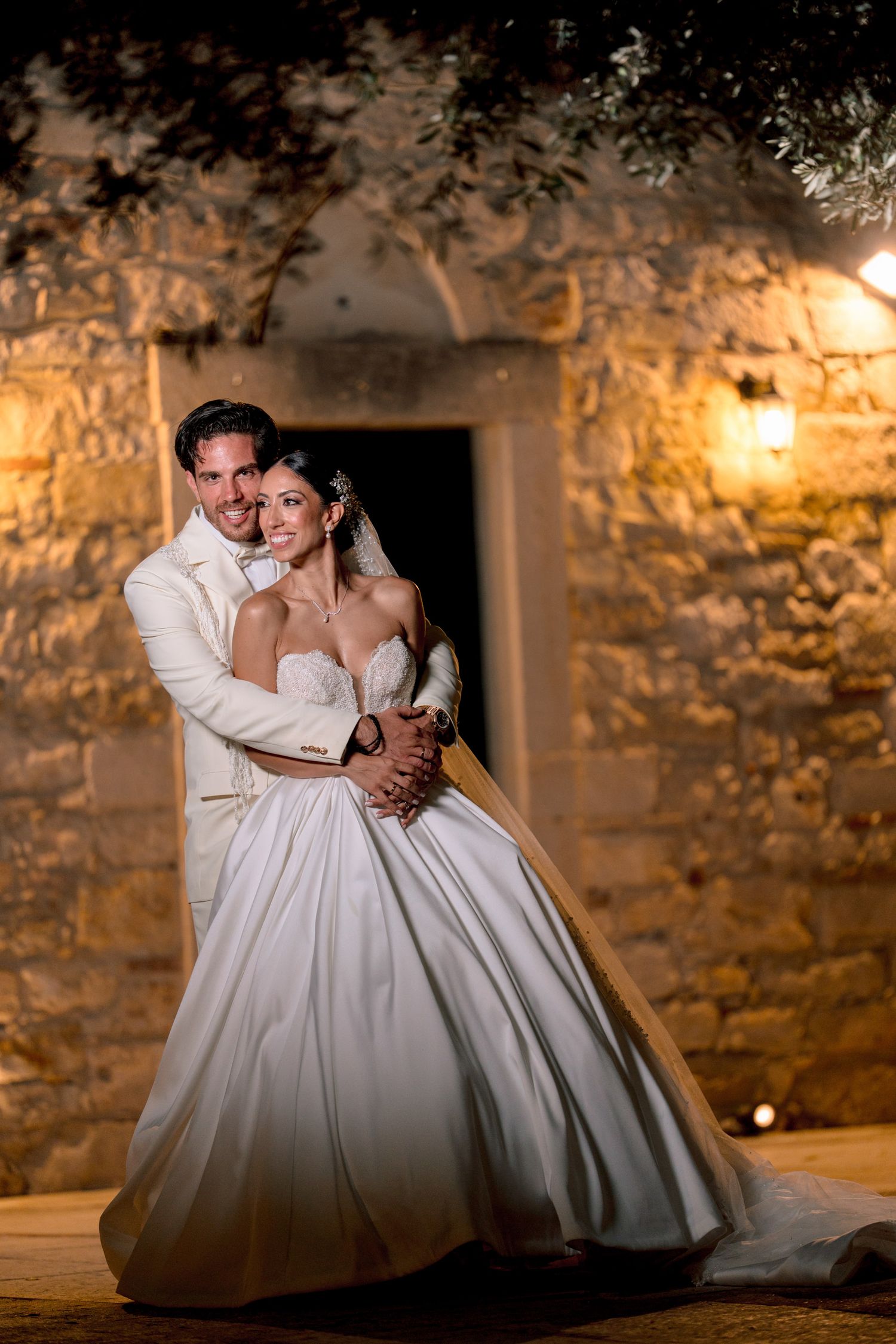 Romantic wedding portrait with stone walls and ambient lighting creating a dreamy atmosphere.