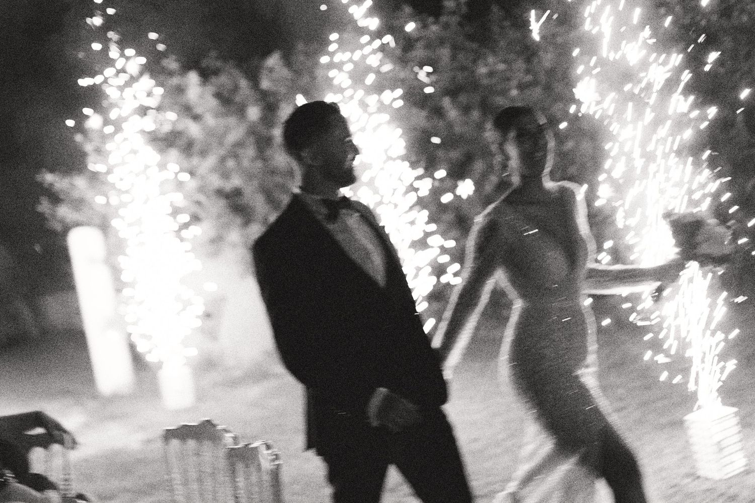 Sparklers create magical light effects during nighttime wedding celebration.