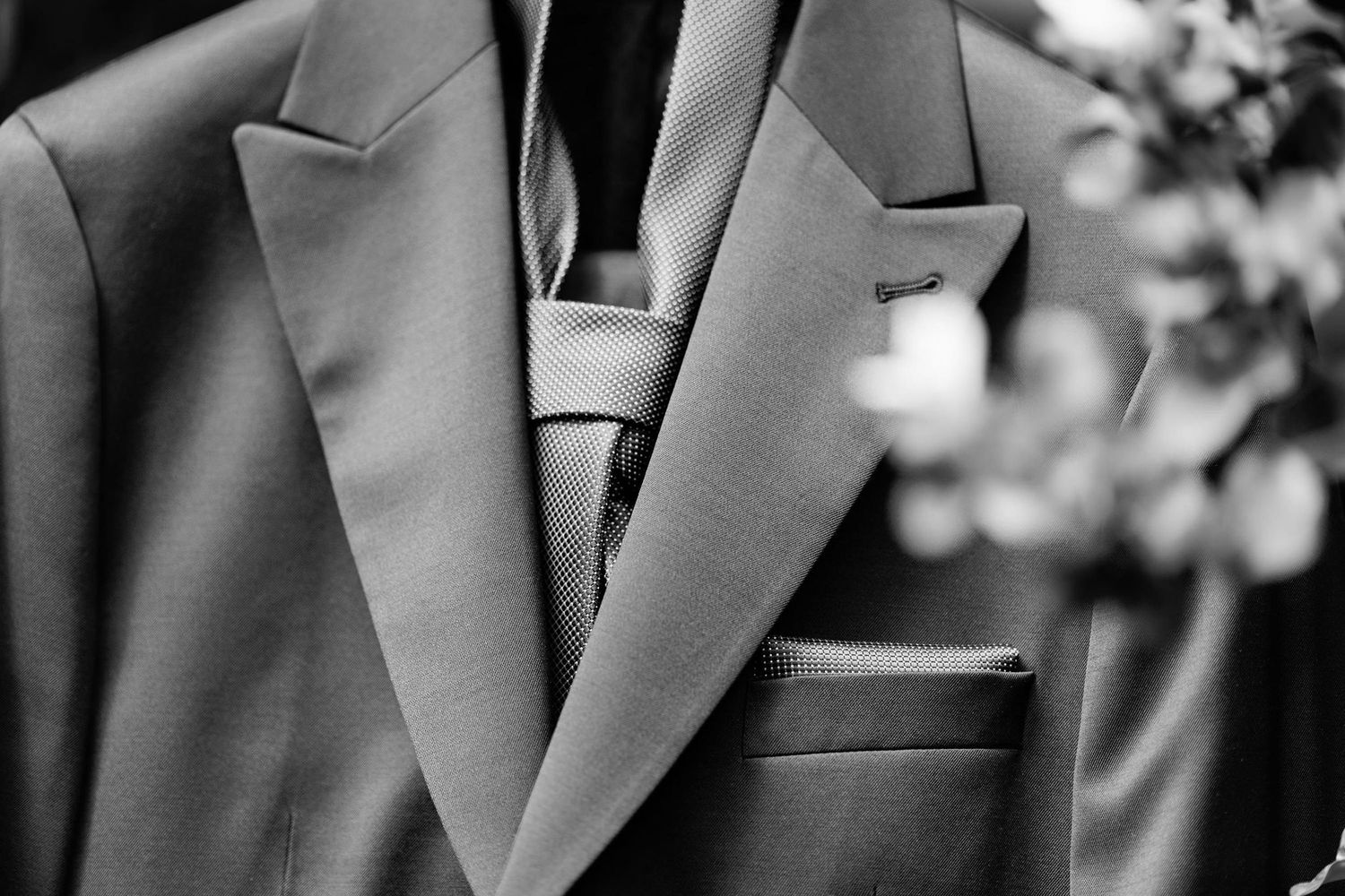 Close-up of a gray suit jacket lapel and pocket detail.