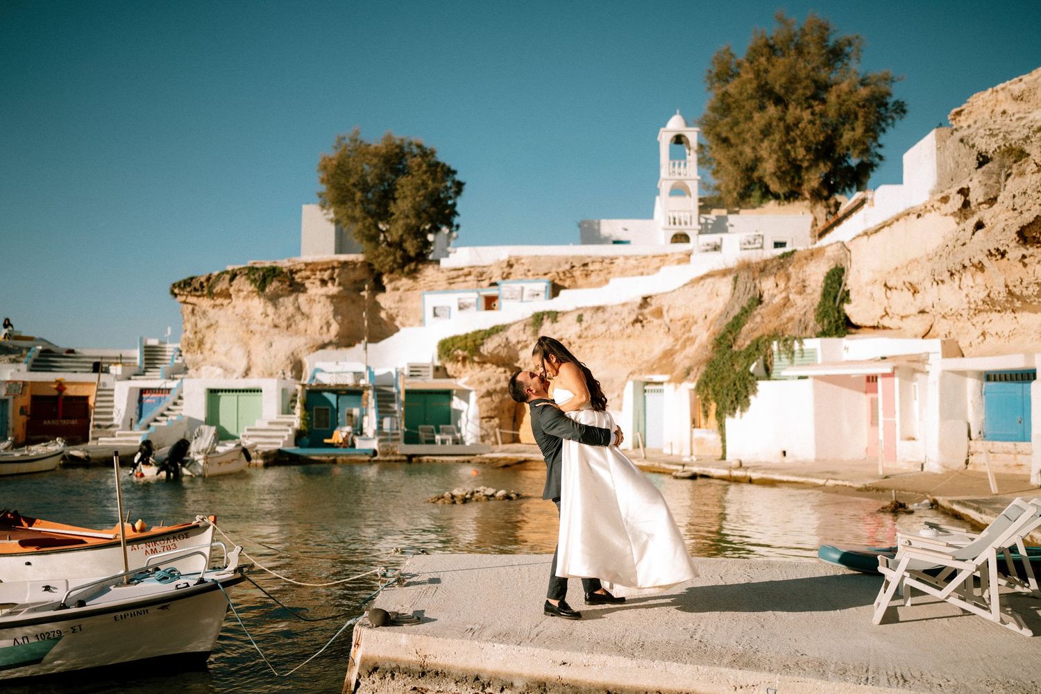 Traditional white Mediterranean village with boats docked along the coastline.