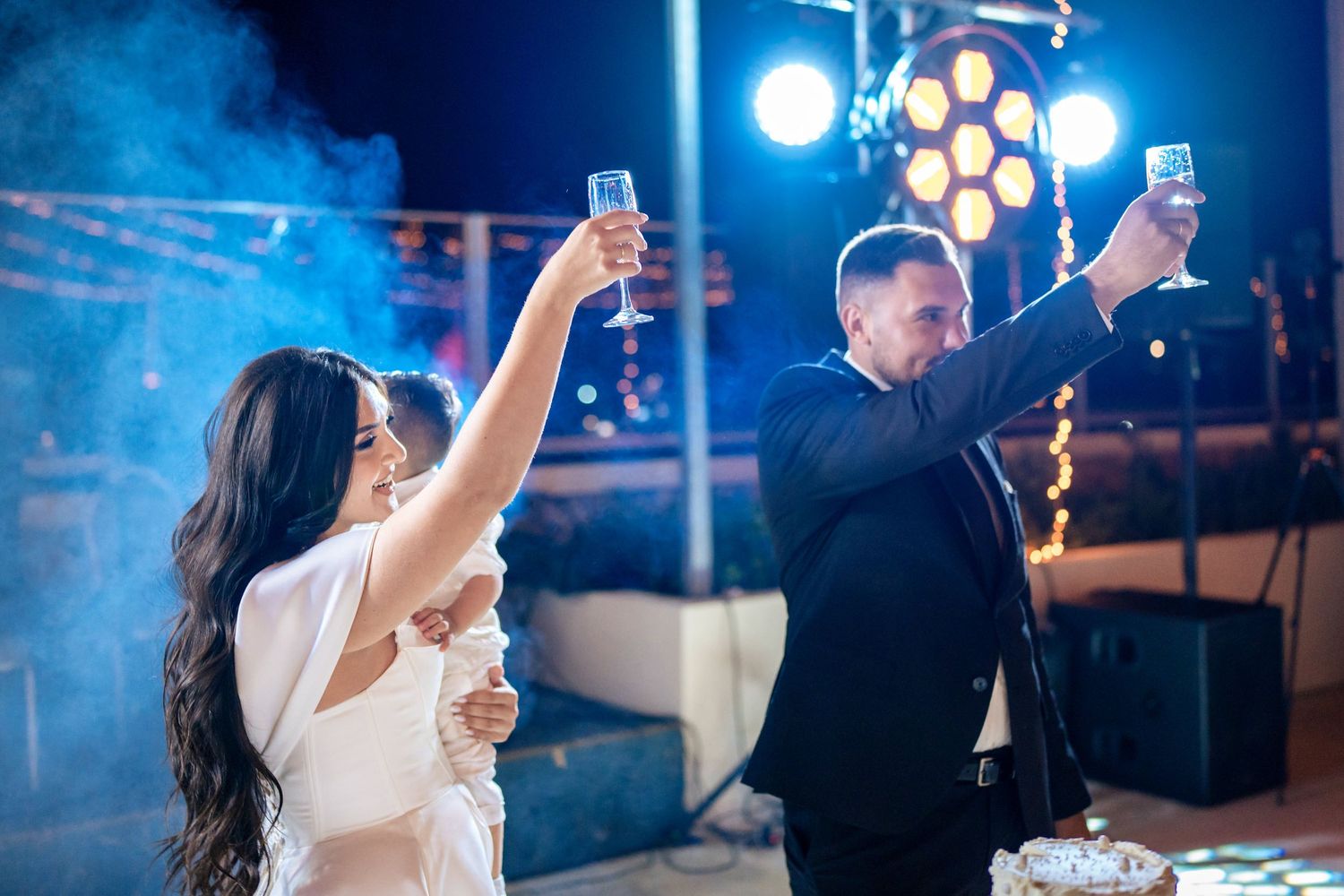 Couple sharing a romantic dance moment under blue stage lighting at an evening reception.