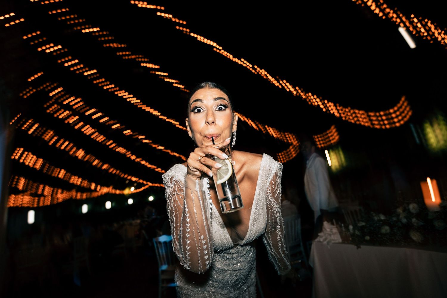 Dramatic nighttime party scene with orange string lights creating patterns overhead.