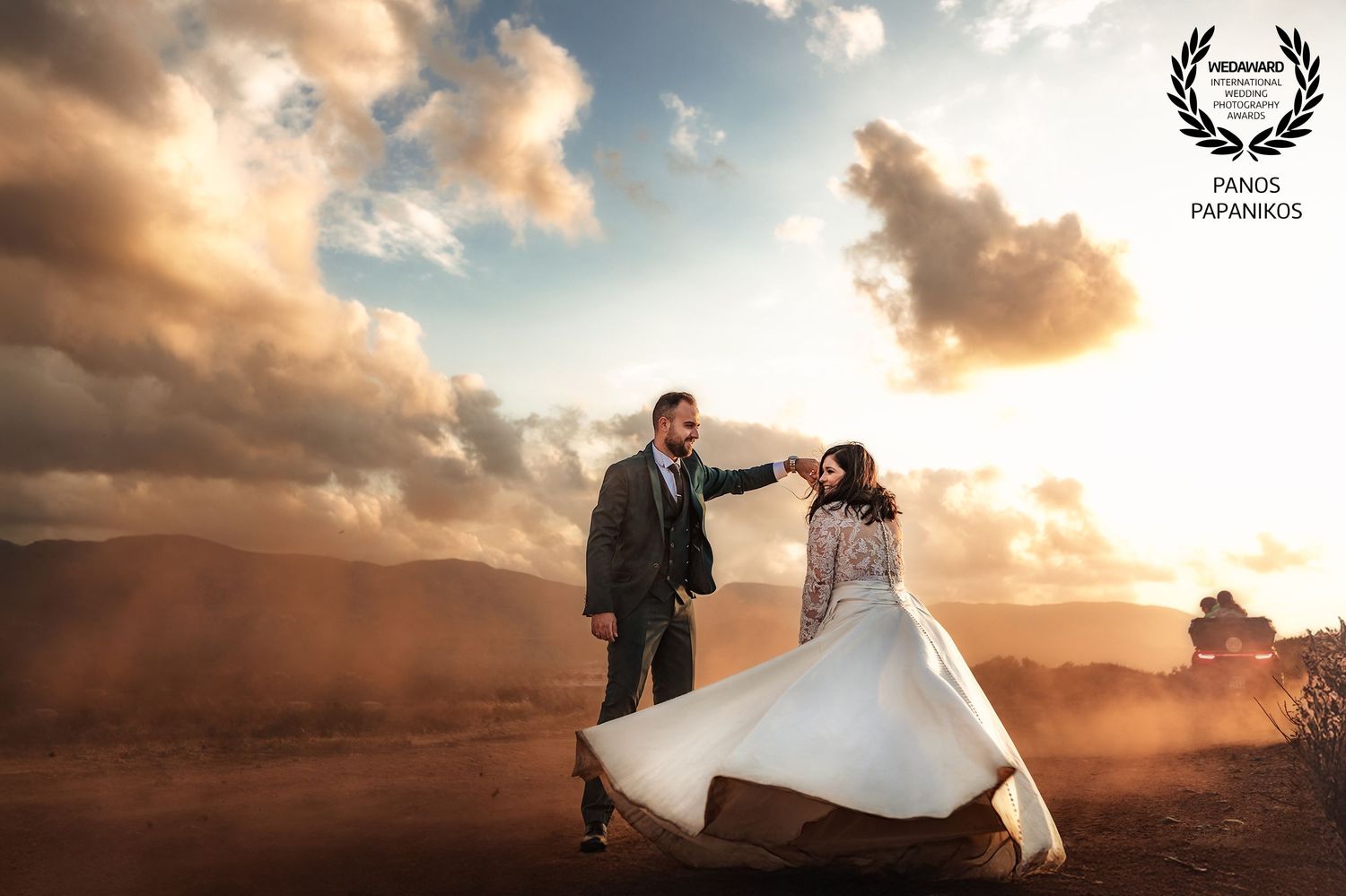Romantic wedding couple dancing together against a dramatic sunset sky with clouds.