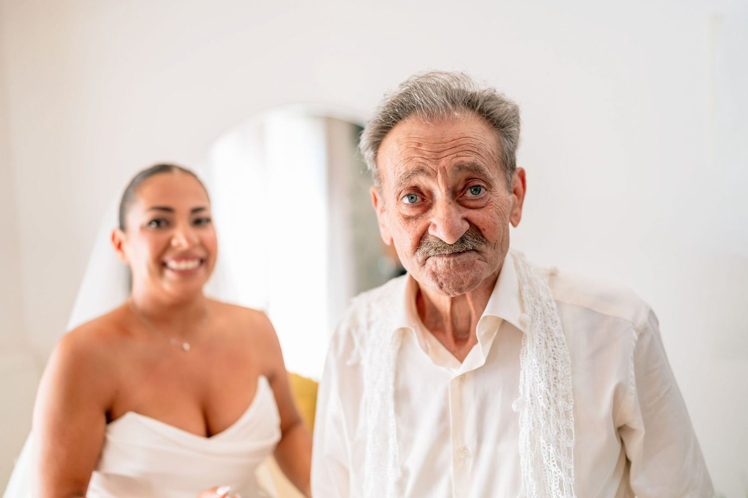 Joyful interaction between two people in white formal attire.