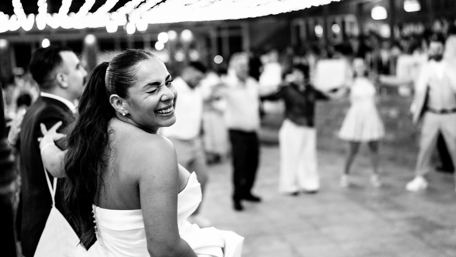 Joyful dancing captured in black and white at an outdoor wedding celebration.