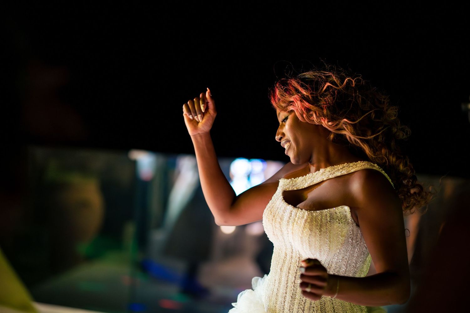 A bride dances joyfully at her wedding reception in a strapless white gown.