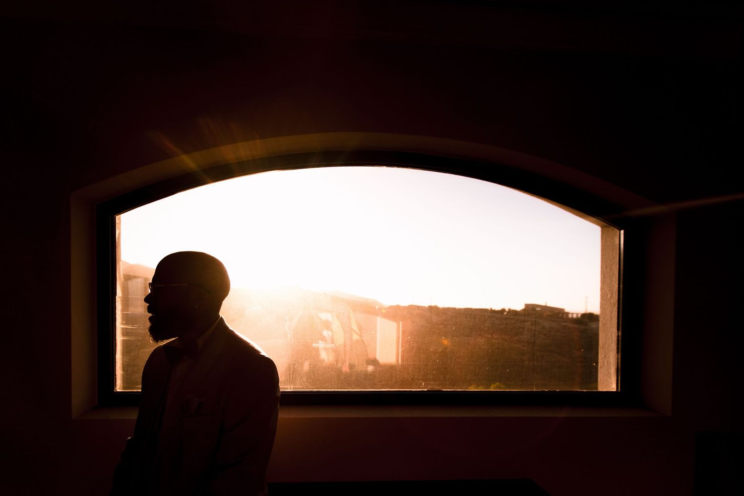 Dark silhouettes against window light create a moody panoramic composition.