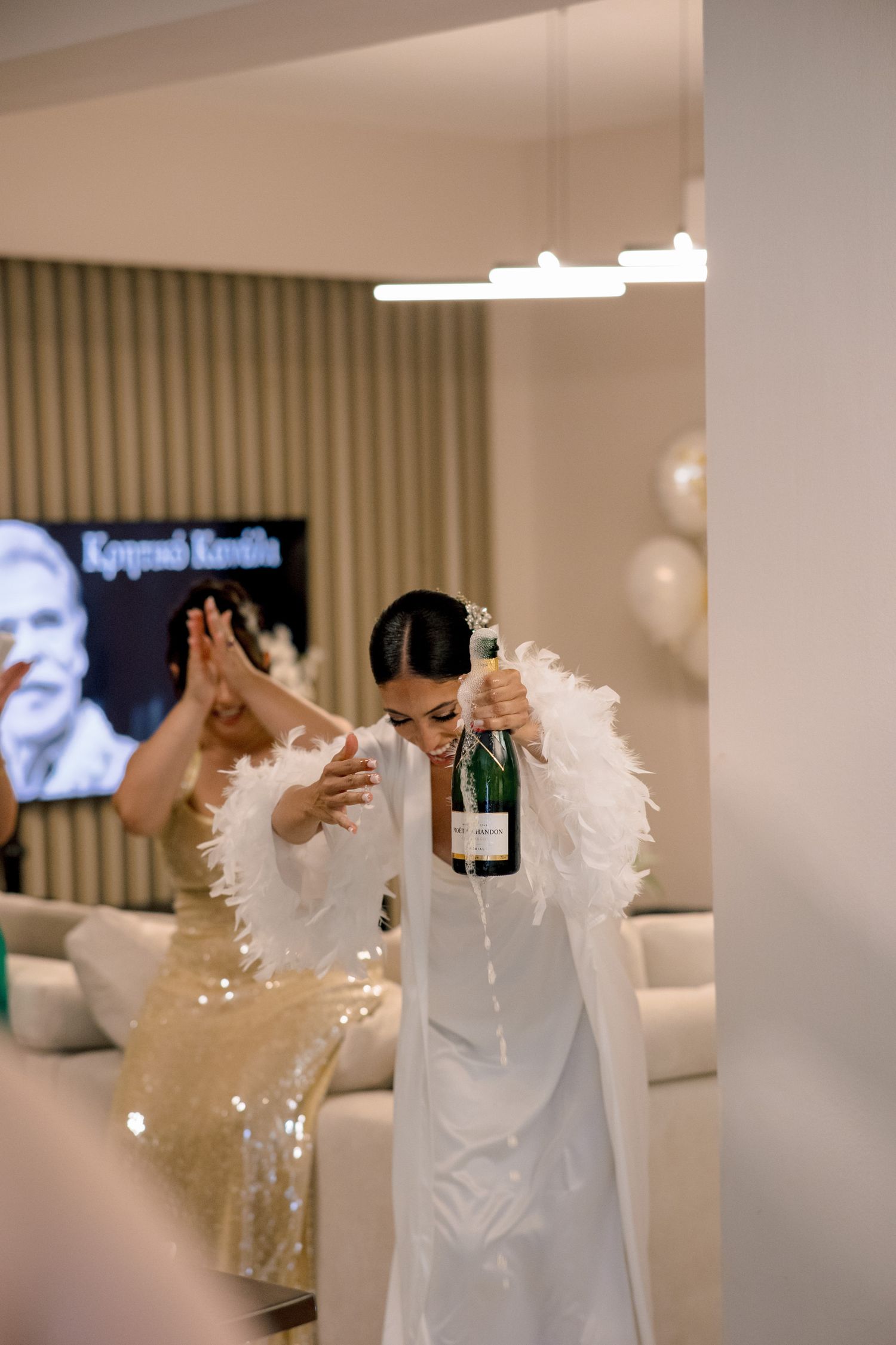 Festive champagne popping celebration with white feather accents.