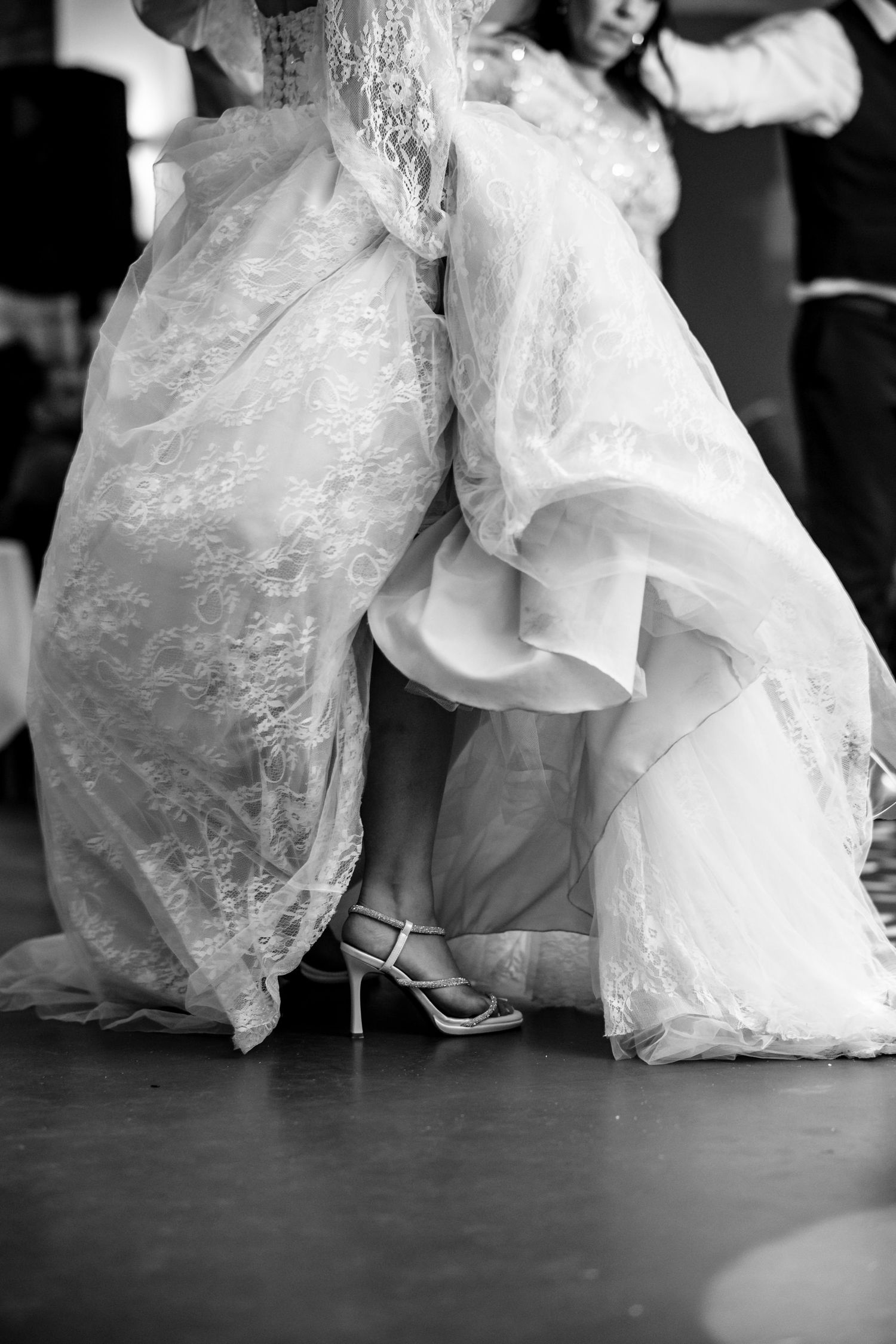 Black and white detail shot of bride's wedding dress flowing during dance.