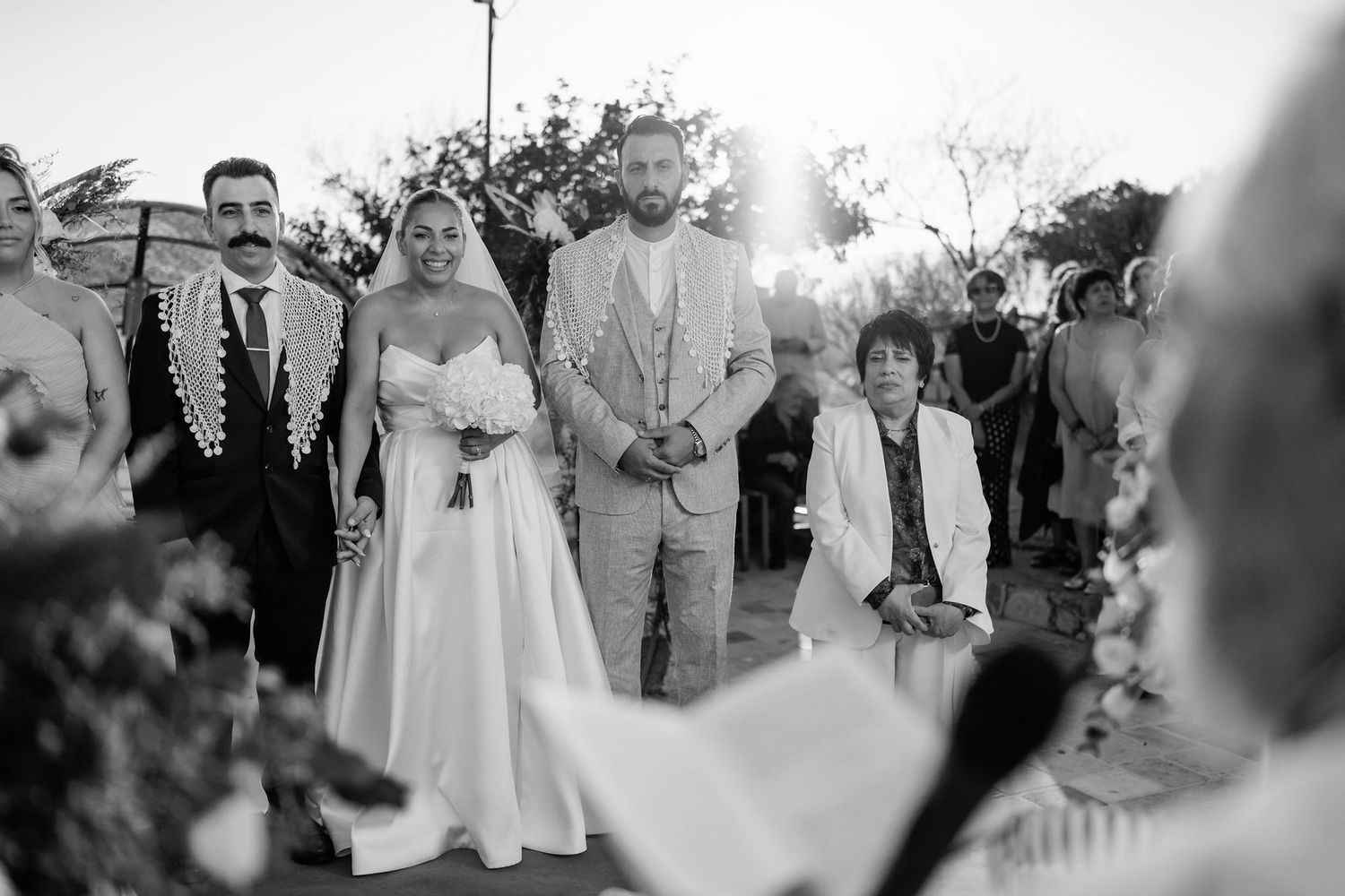 Black and white photo of wedding guests enjoying outdoor celebration.
