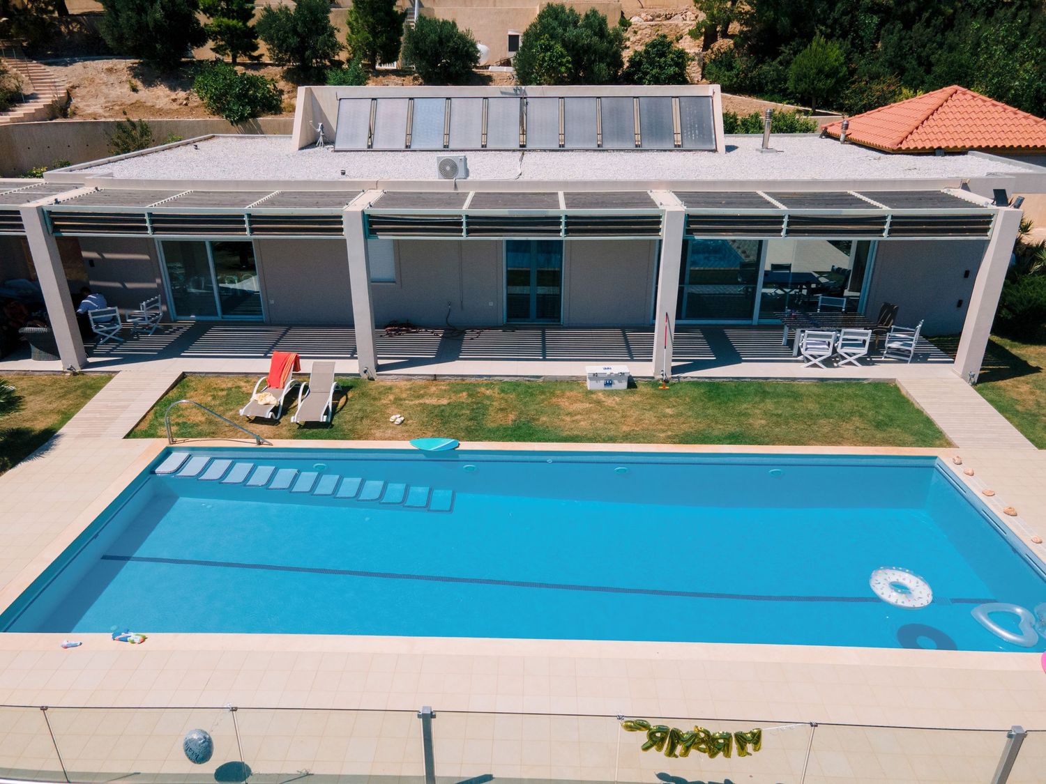 Modern house with a rectangular swimming pool and patio area viewed from above.