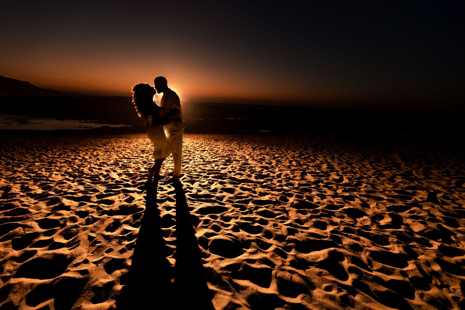 Romantic silhouettes against desert landscape at golden hour.
