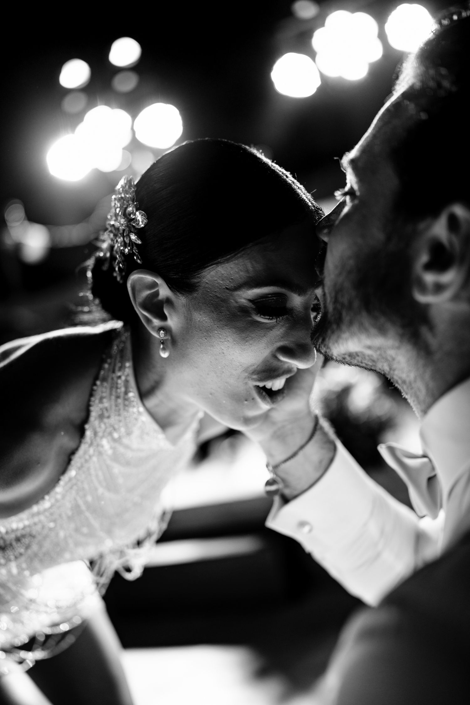 Intimate black and white moment captured during a celebration under ambient lighting.