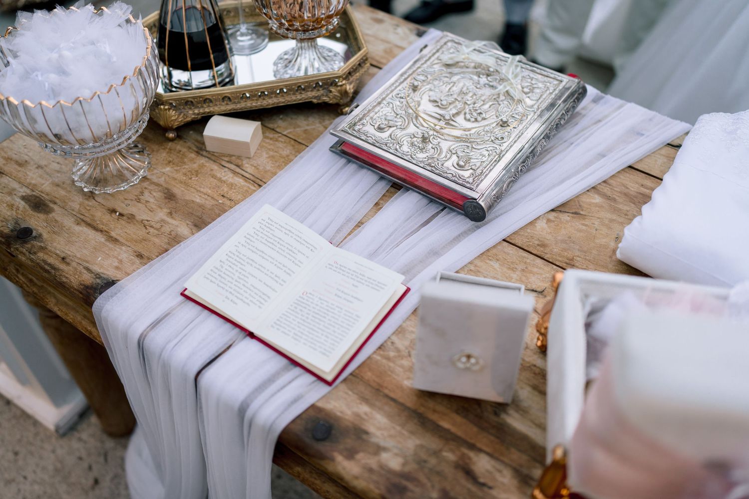 Traditional wedding ceremony items arranged on rustic wooden table with white linens.