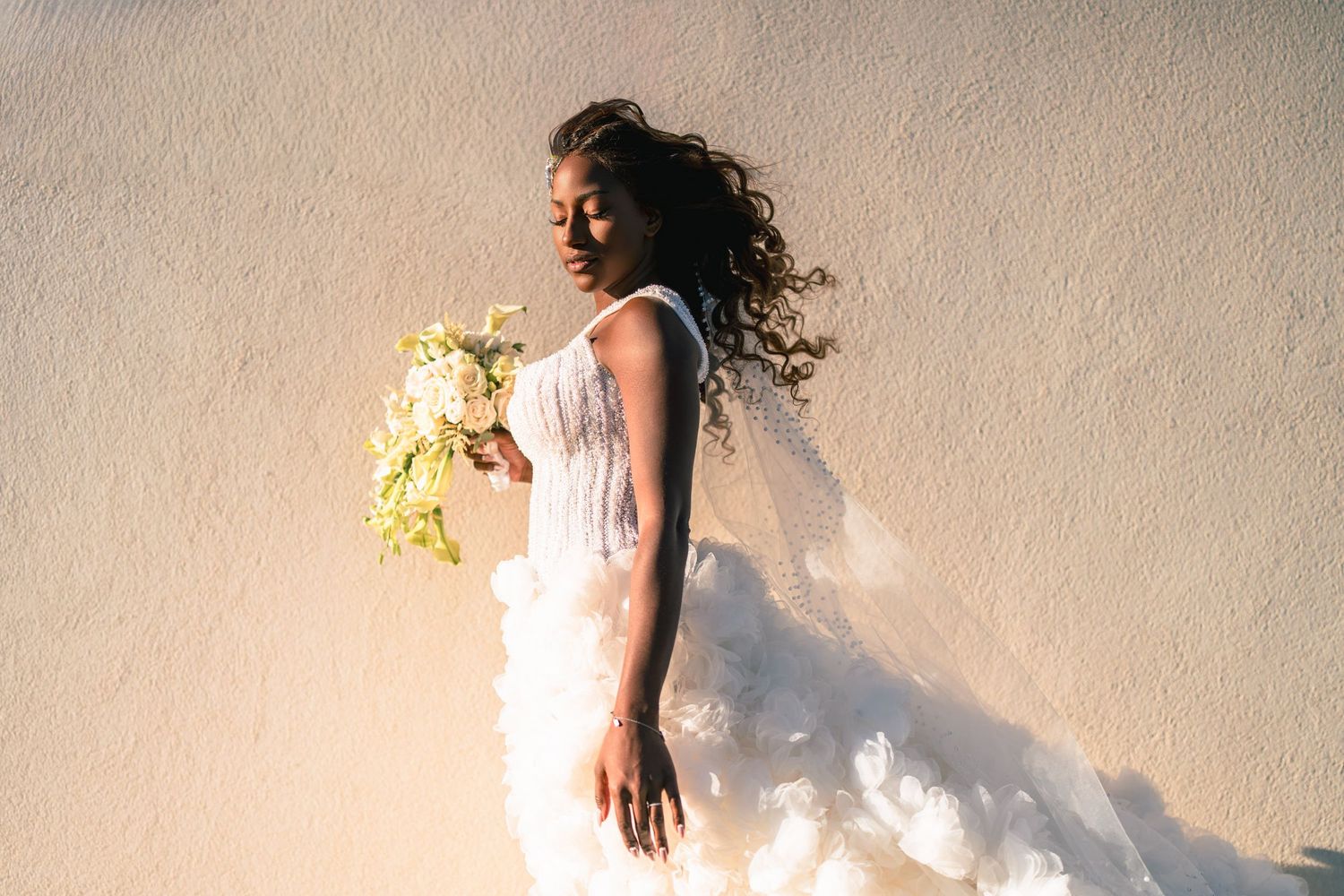 Elegant wedding dress details with flowing fabric against a neutral wall.