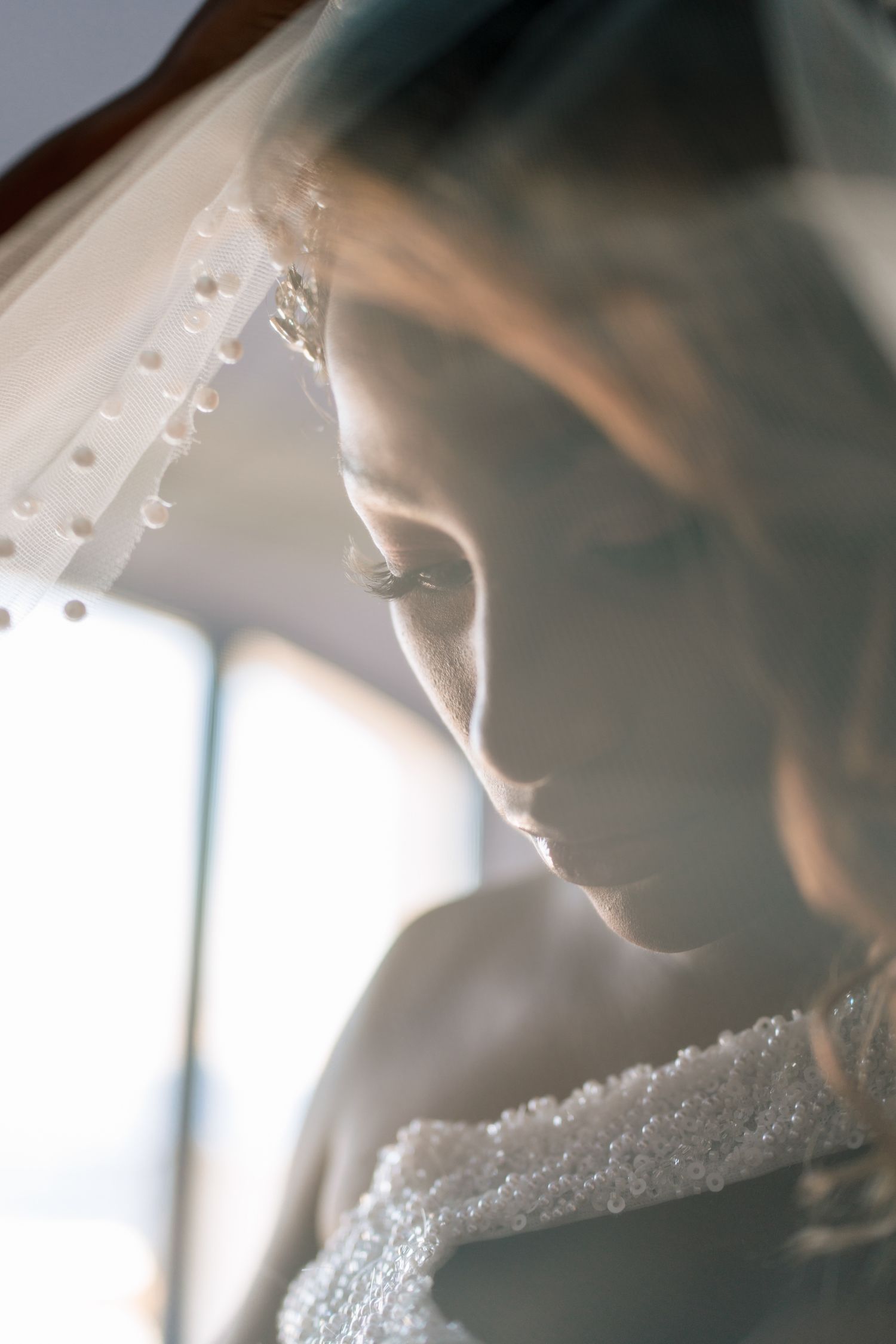 Artistic silhouette of a bride in natural window light showing the details of her wedding dress.