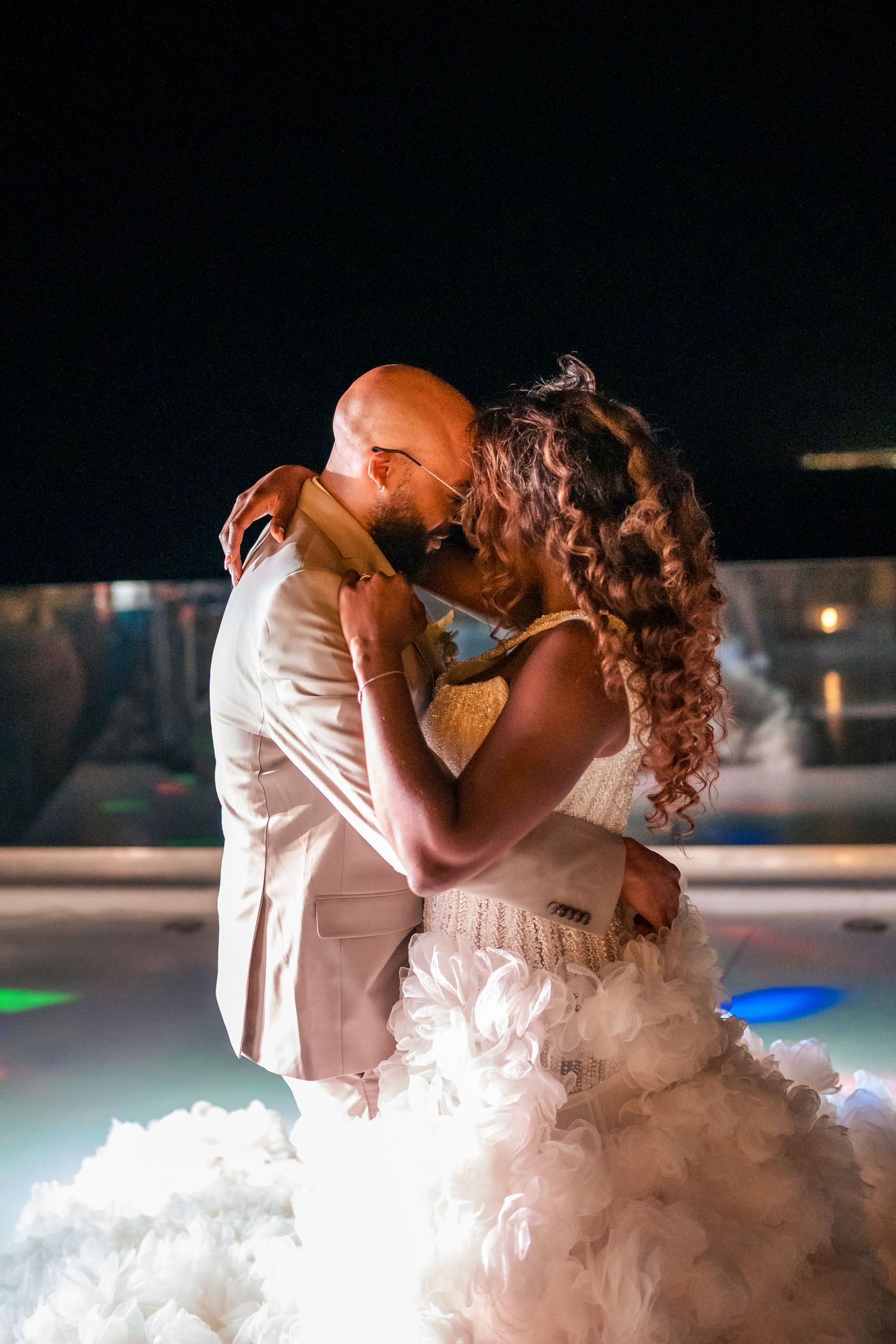 A romantic dance moment captured on an illuminated dance floor with a flowing white dress.