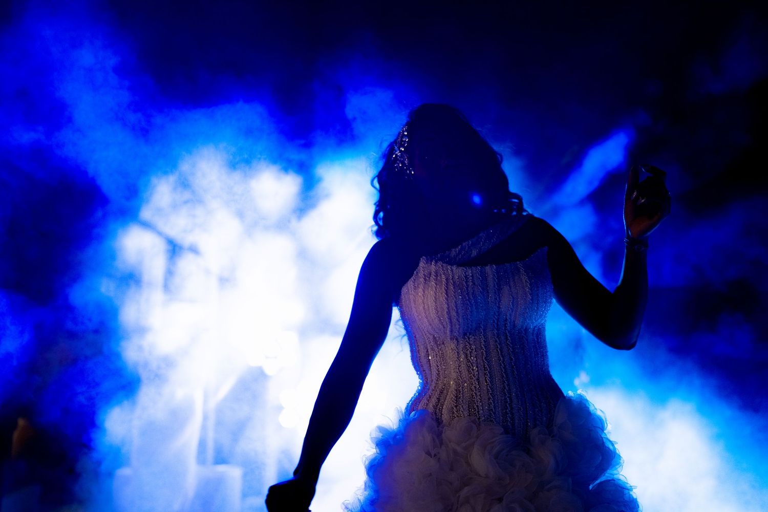Dancers silhouetted against atmospheric blue smoke effects.