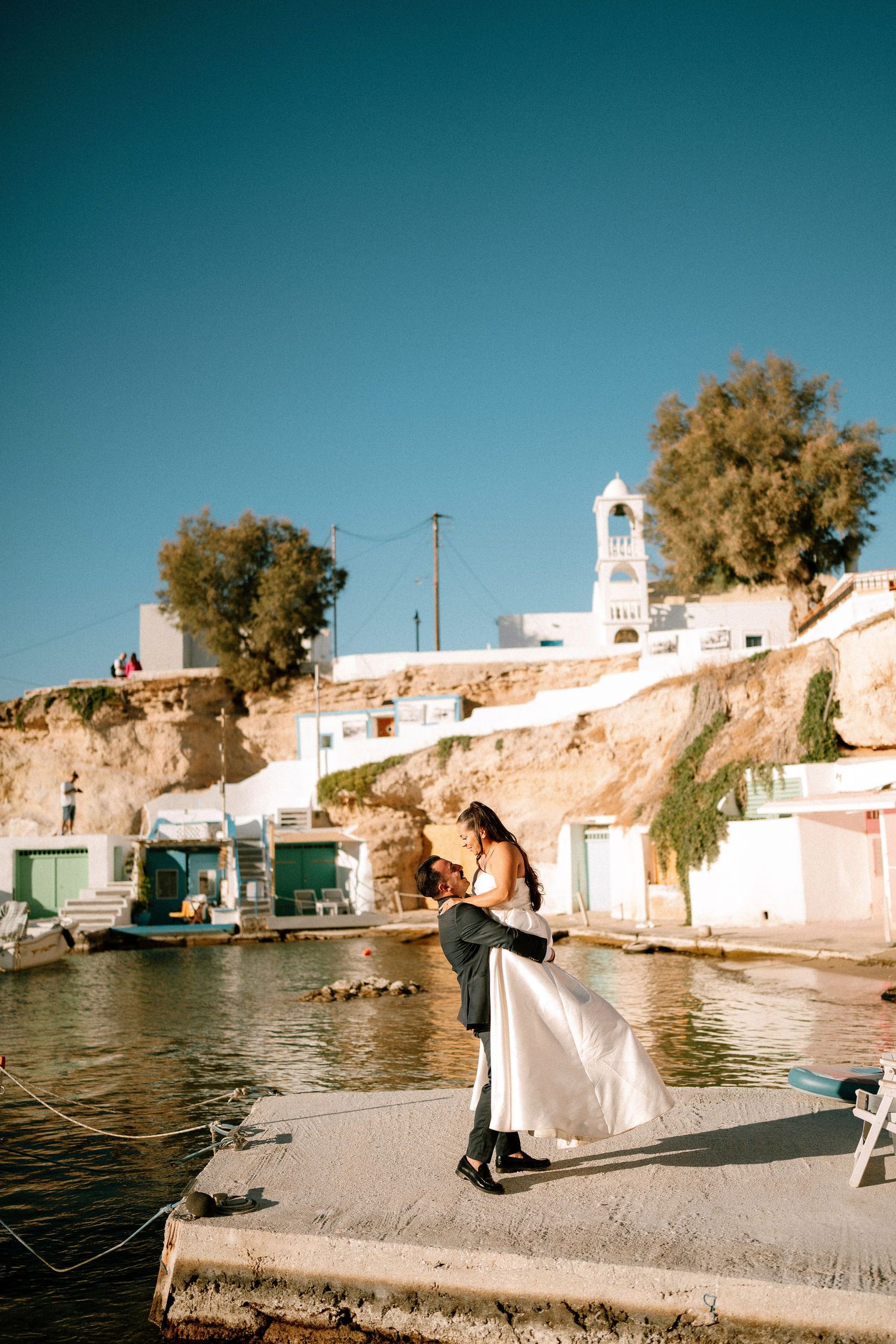 White coastal village buildings with boats docked along the Mediterranean shoreline.