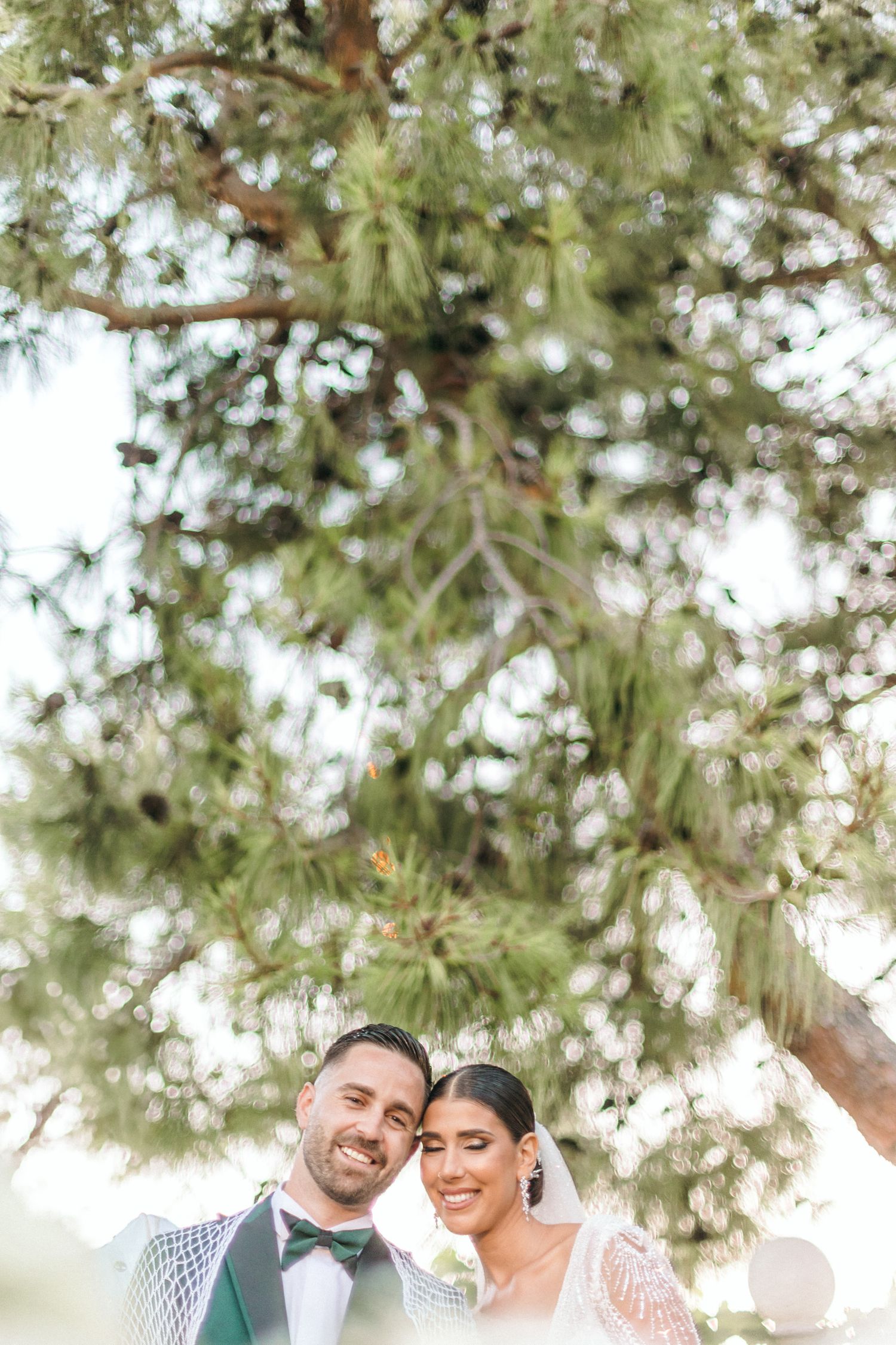 Wedding couple under pine trees in natural outdoor setting.