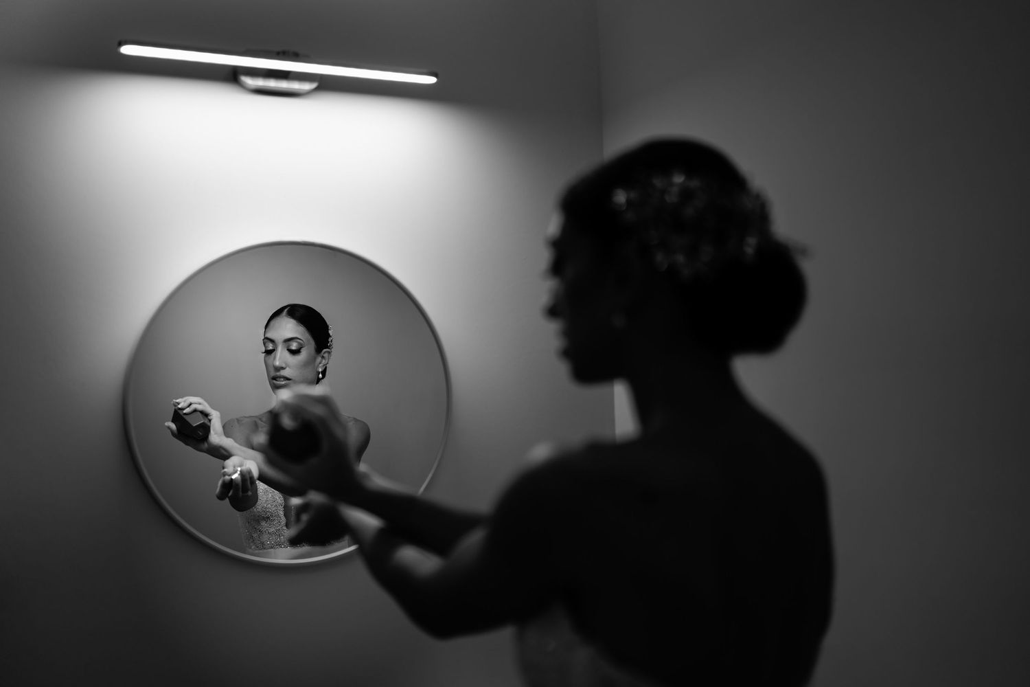 Dramatic black and white shots of silhouettes reflected in oval mirrors.
