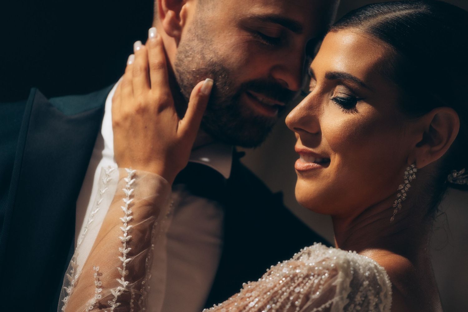 Intimate close-up of newlyweds sharing tender moment in formal attire.