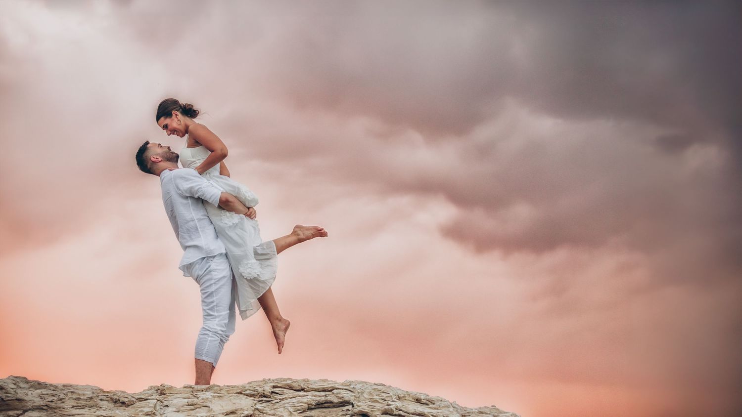 Couple embraces in ocean water during dreamy sunset photography session.