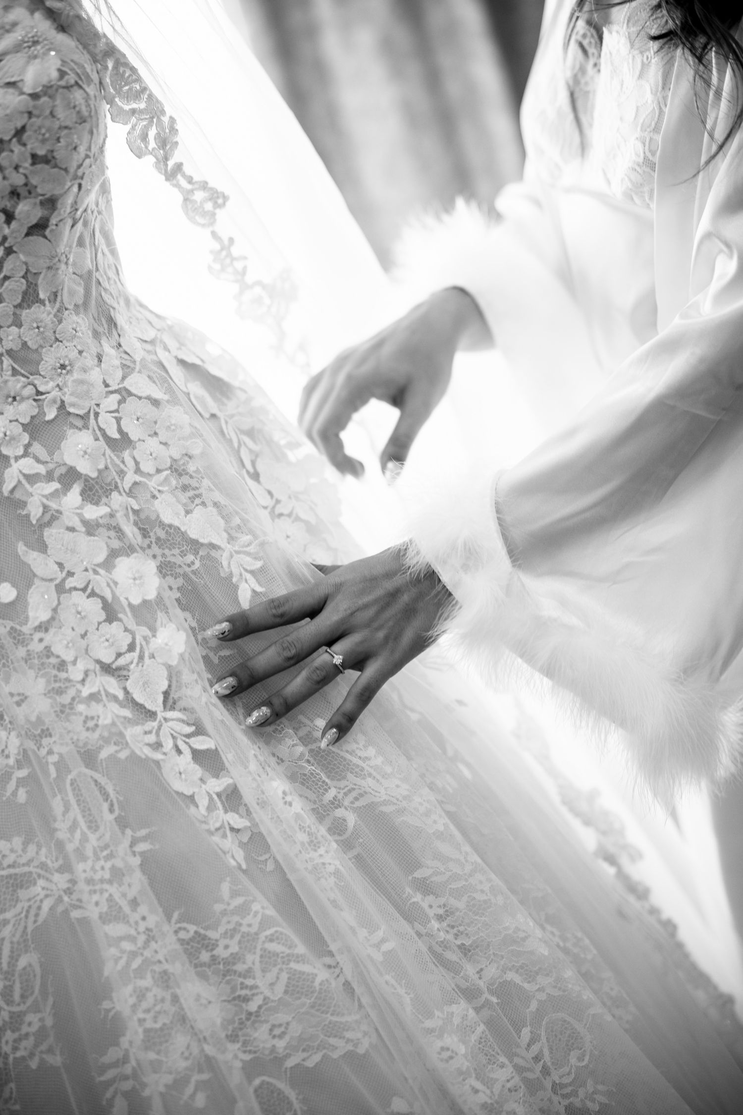Close-up details of white lace wedding dress fabric with intricate floral patterns.