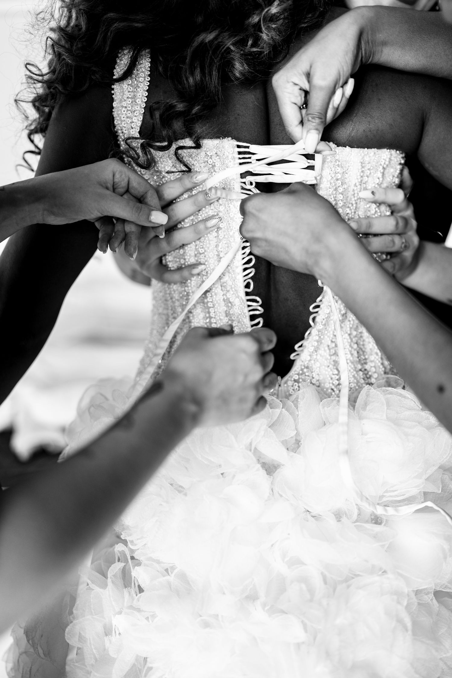Close-up details of a bride getting dressed in an elegant white wedding gown with delicate lace details.
