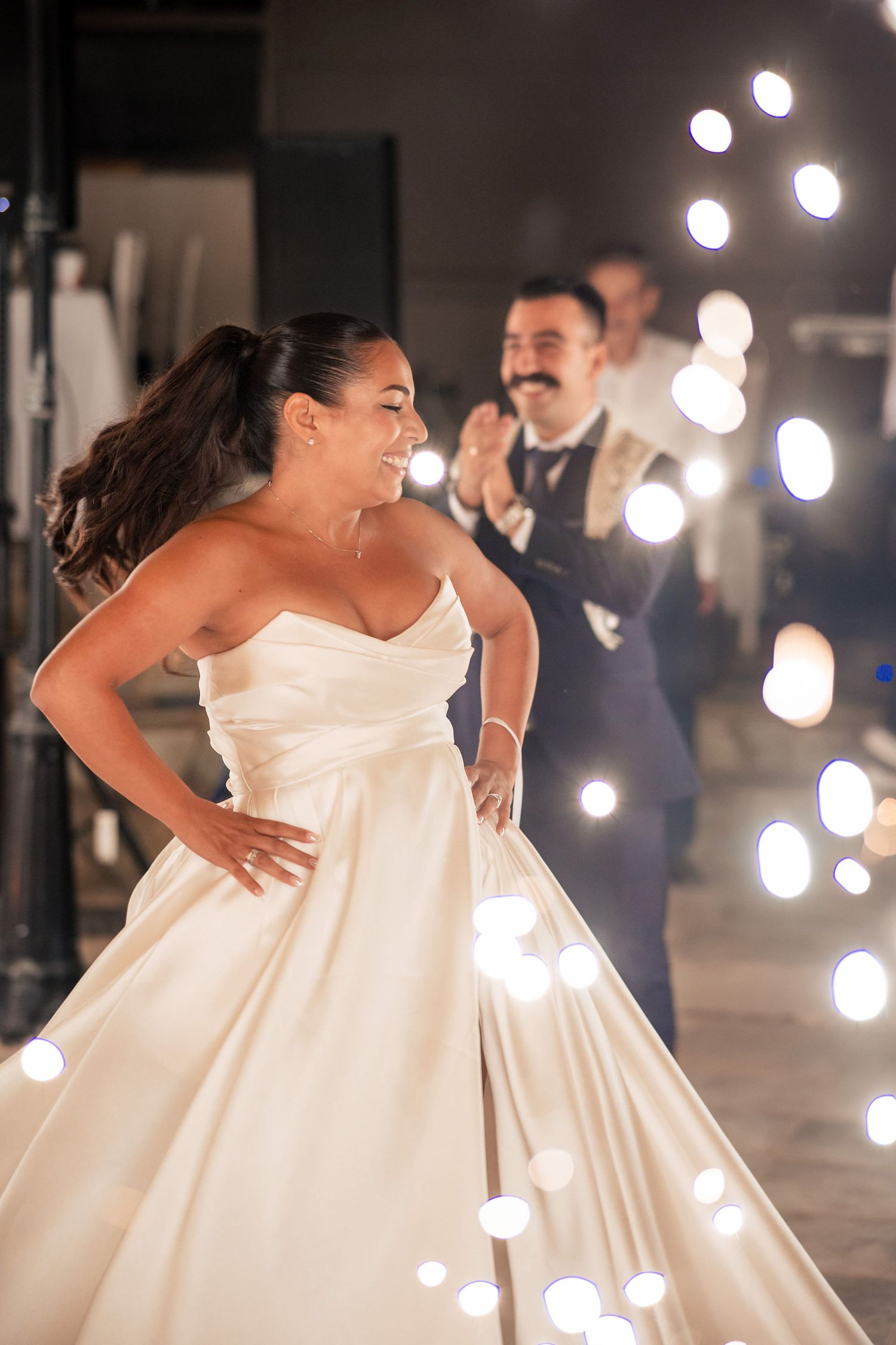 A couple dances under glowing string lights at an elegant evening reception.