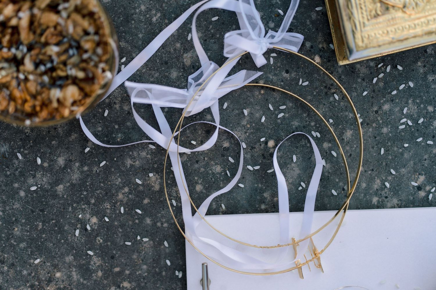 White ribbon and wedding details arranged on a dark textured surface.