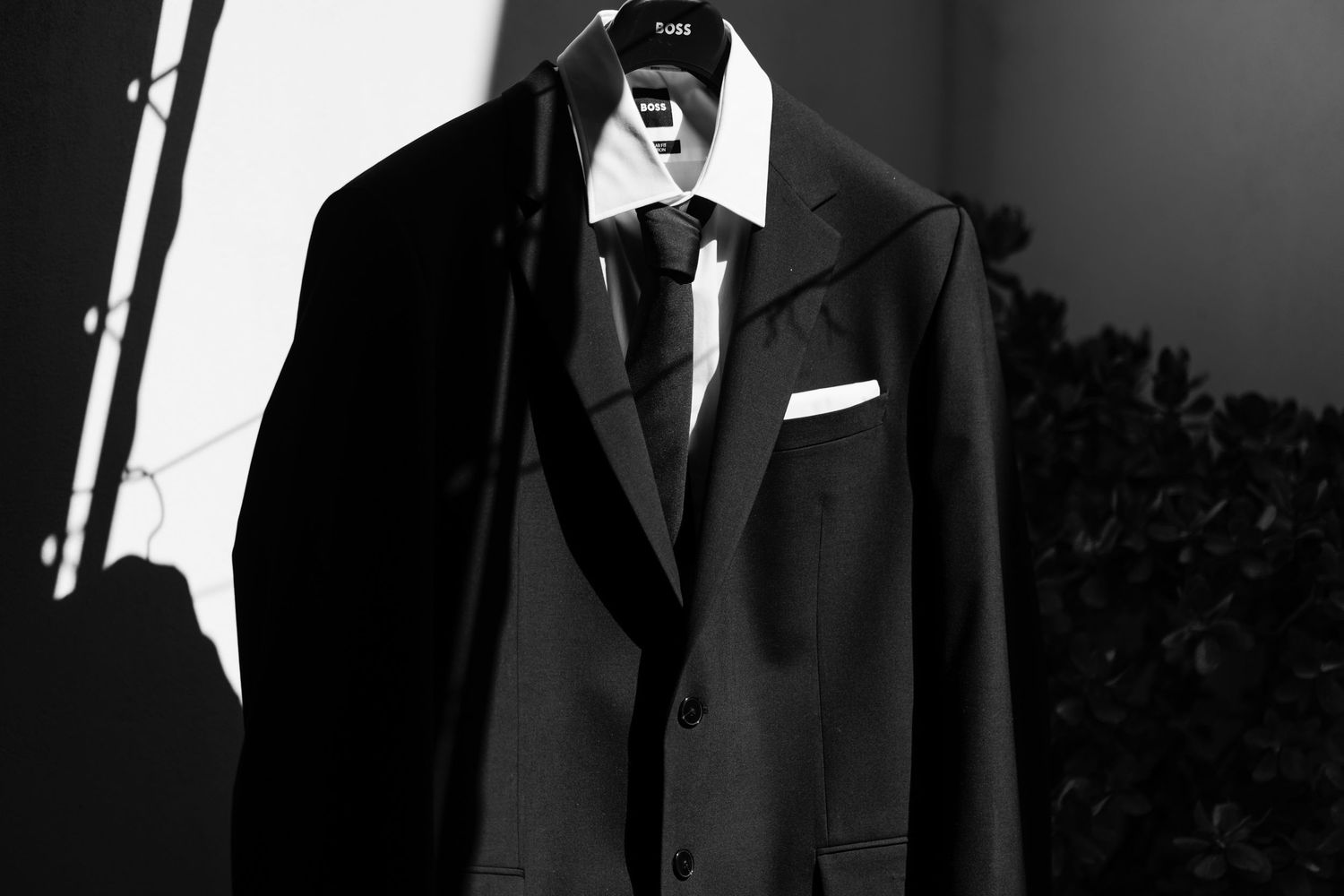 Classic black tuxedo jacket with white shirt and tie displayed against dark background.
