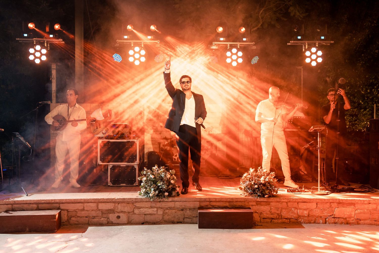Live wedding band performing on stage with dramatic orange lighting and smoke effects.