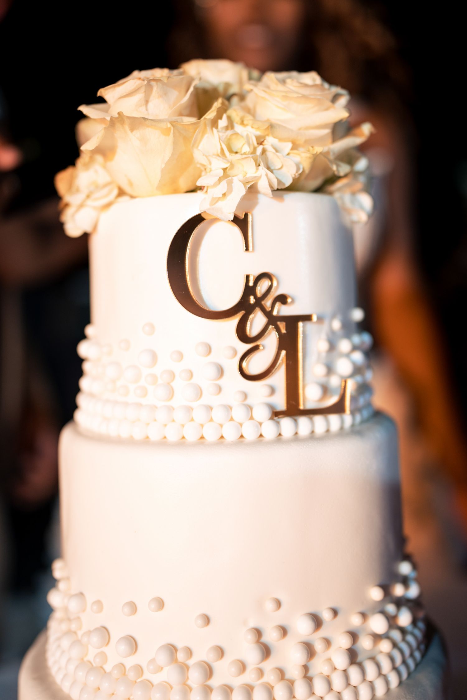 Elegant white wedding cake with decorative details and monogram toppers.