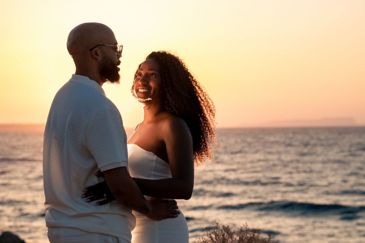 Romantic beach photoshoot with couple against sunset and ocean waves.