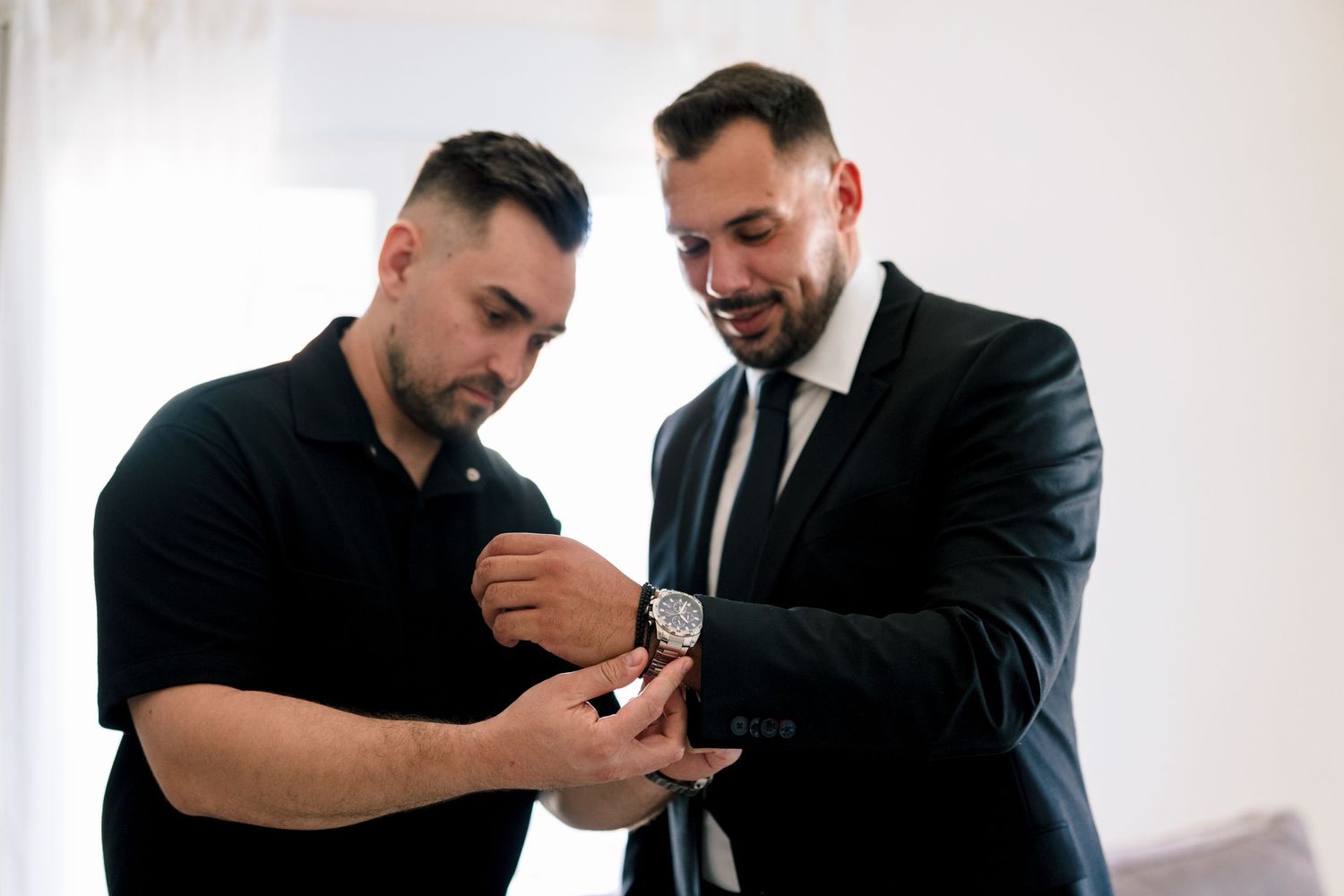 Men in formal wear helping each other prepare and adjust clothing.