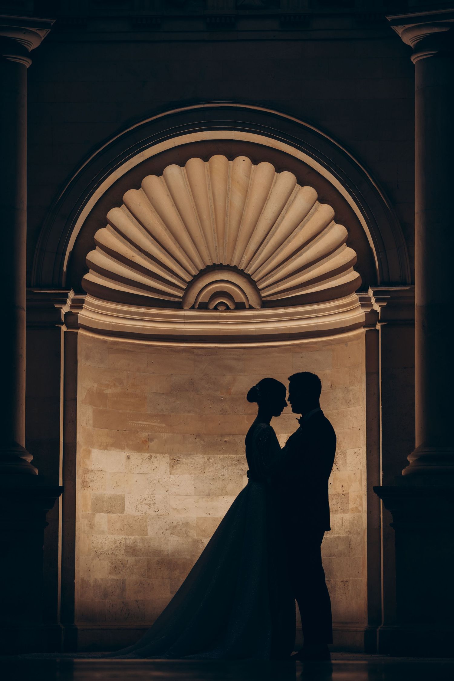Romantic silhouette of couple under ornate architectural arch.