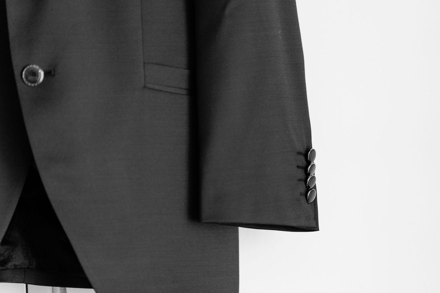 Close-up detail of a black suit jacket sleeve and button.