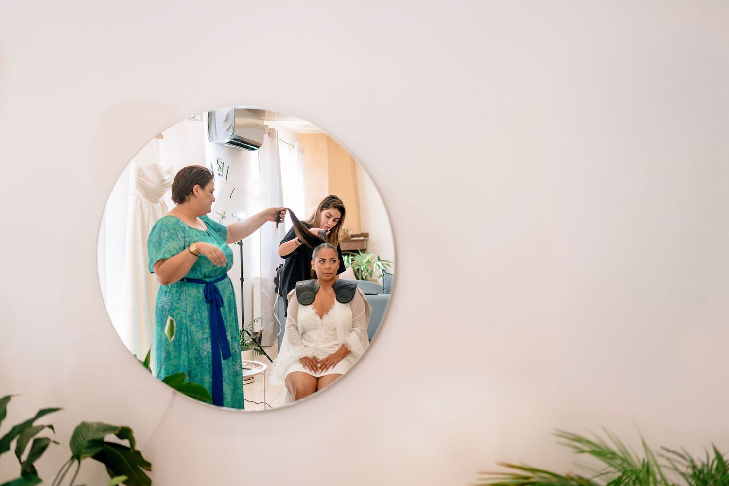 Round mirrors mounted on wall reflecting a styling session in progress.
