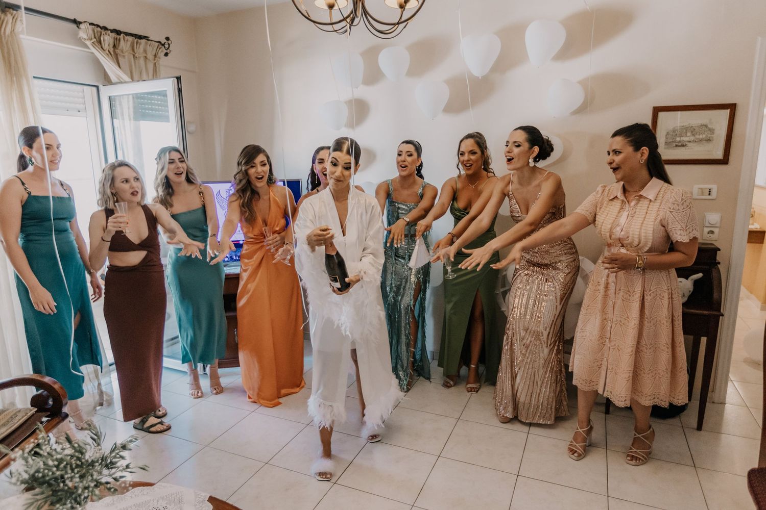 Wedding party in coordinated dresses of teal, orange and neutral colors pose together.