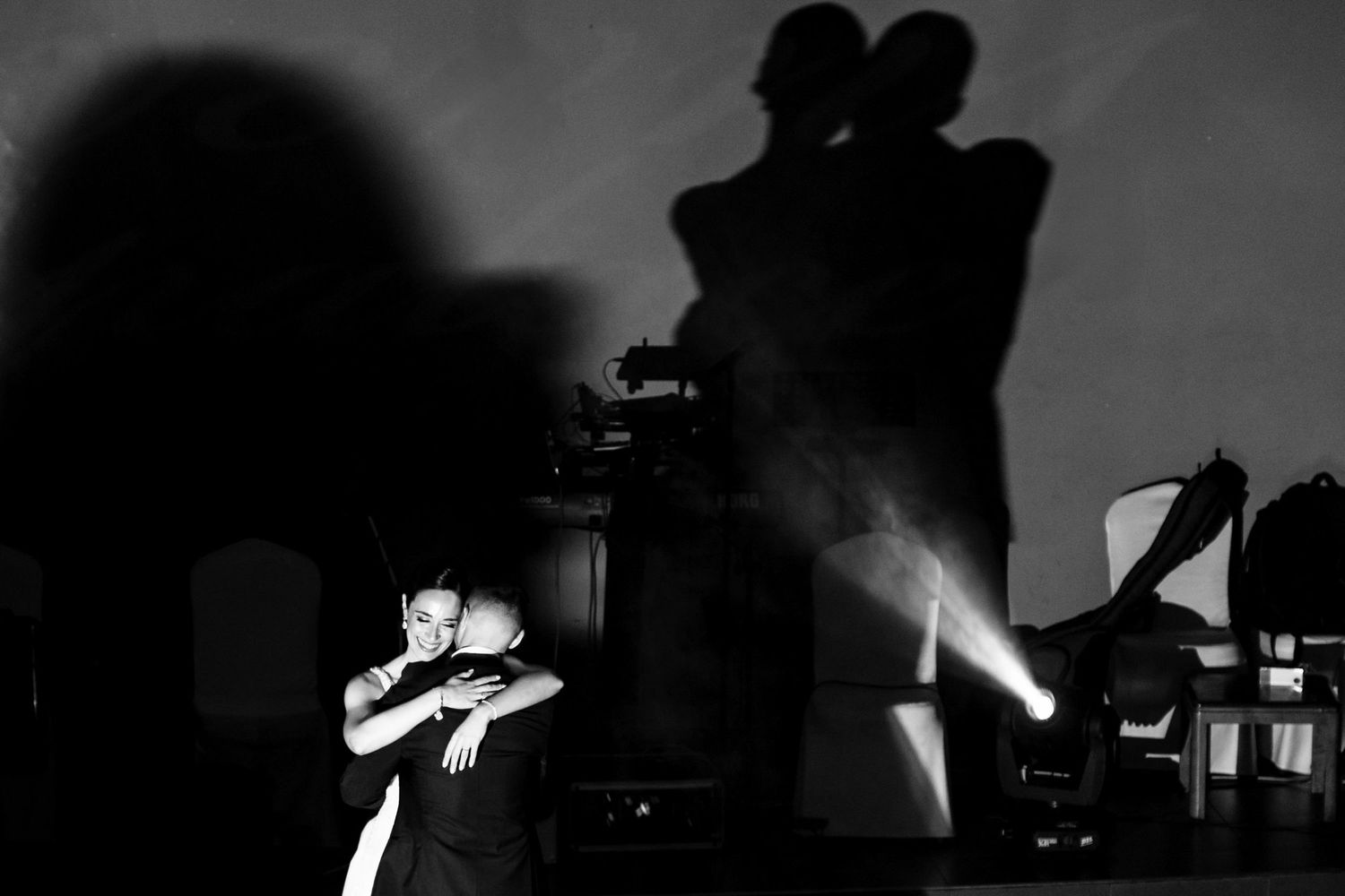 Silhouetted wedding reception scene with dramatic lighting and dancing.