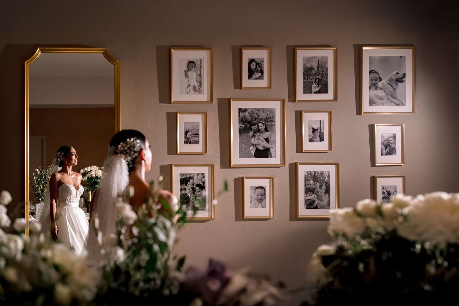 A wall gallery of black and white photographs with flowers in the foreground.