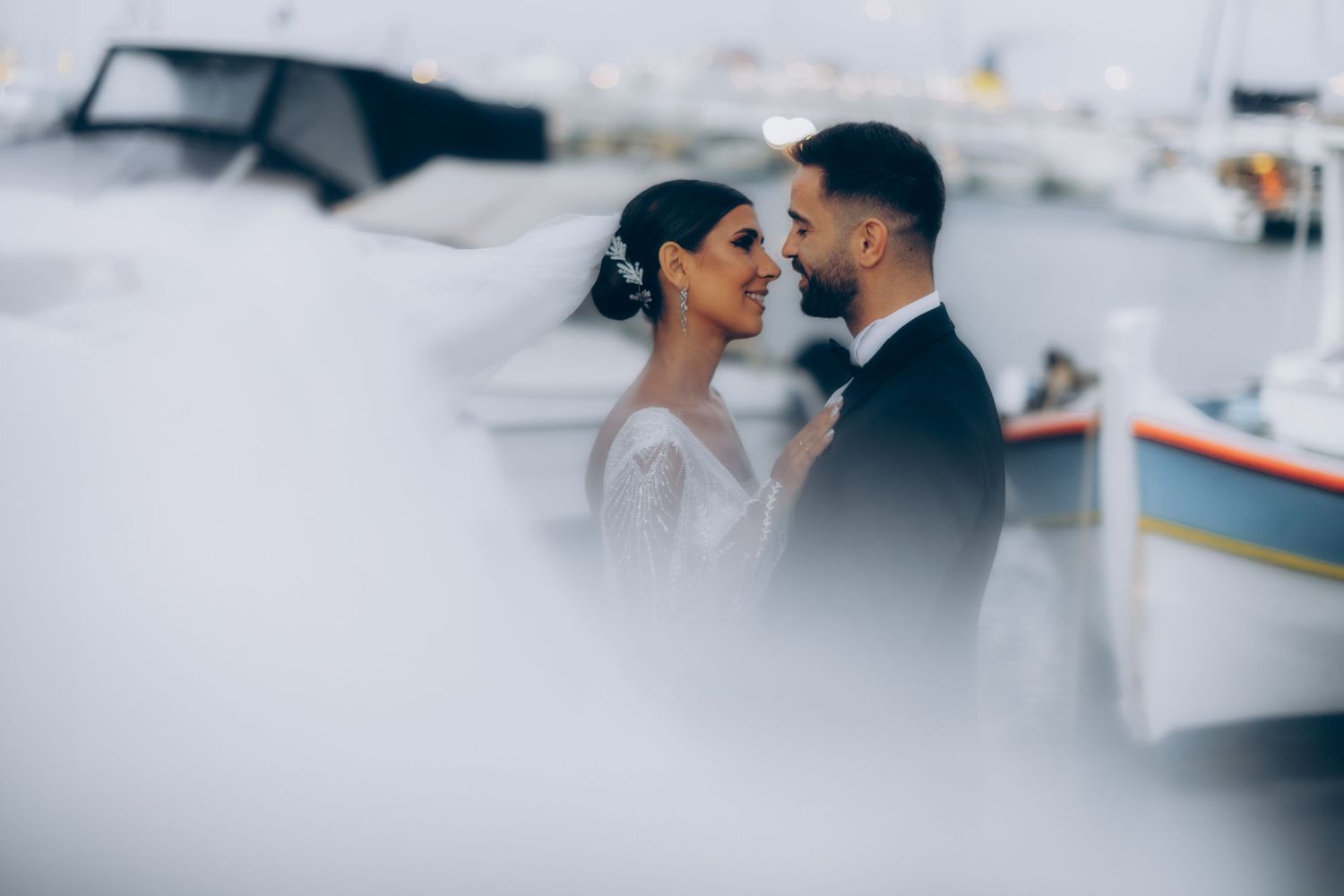 Intimate wedding portrait captured through foreground elements creating a soft focus effect.