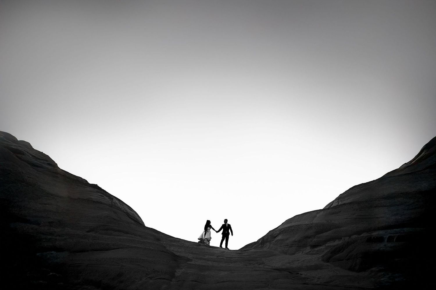Silhouettes against a dramatic sunset sky between mountain ridges.
