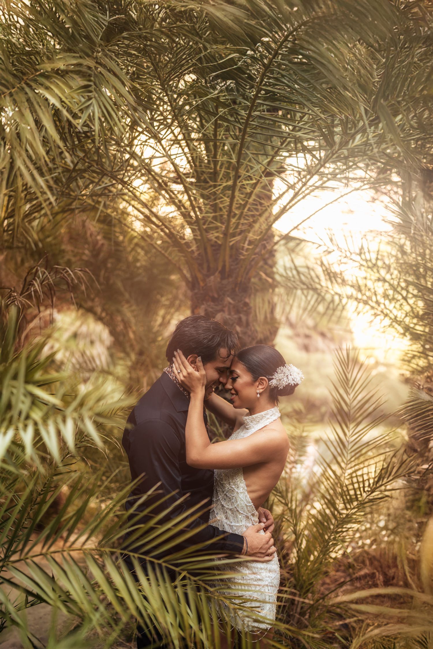 Newlyweds share tender moments beneath swaying palm trees in golden sunlight.