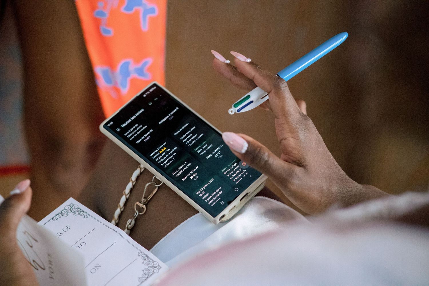 Hand holding phone displaying schedule or timeline with blue pen.